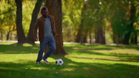 Adult-man-training-soccer-tricks-in-sunny-spring-park.-Happy-player-on-field