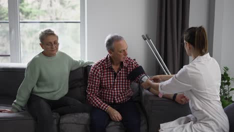 mujer terapeuta midiendo la presión arterial de un anciano en casa