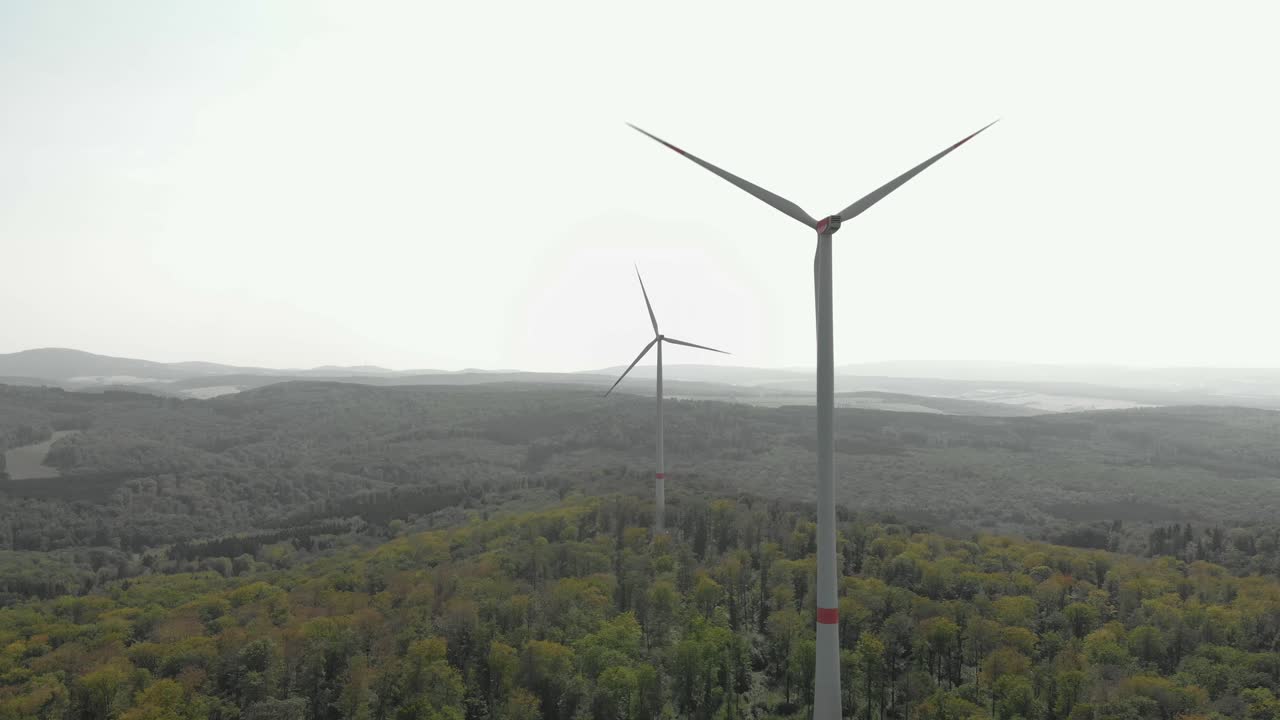 숲, 밝은 일광으로 둘러싸인 두 개의 풍력 터빈의 공중 돌리 샷