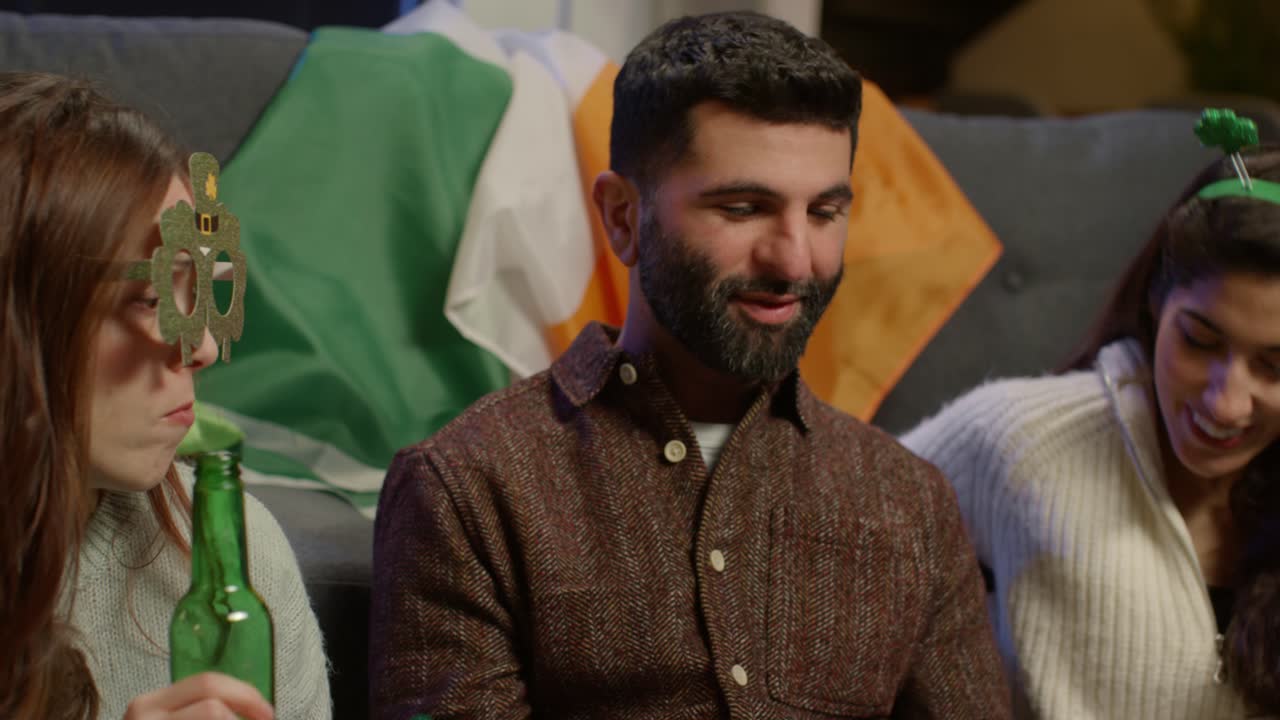 группа друзей одевается дома, празднует день святого патрика, делает видео звонок на мобильный телефон.