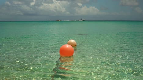 2 floats sitting in turquoise water as boats pass by