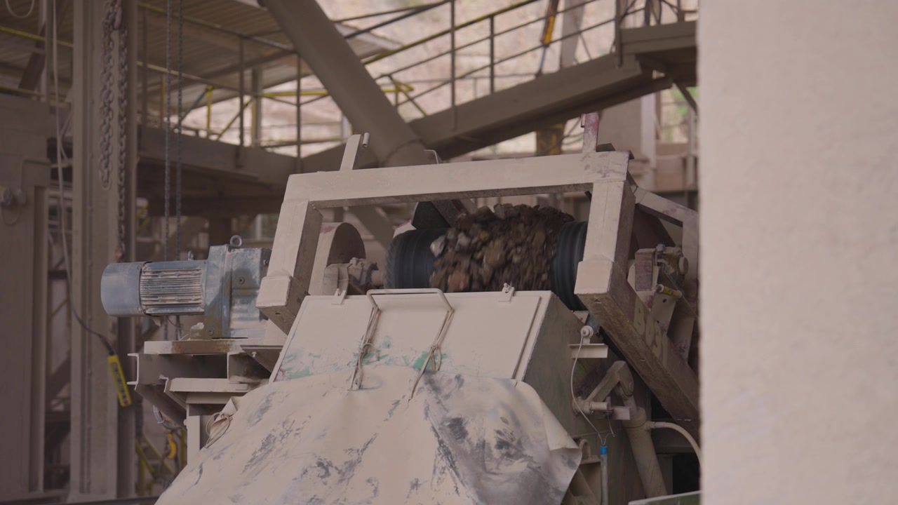 Rock fragments fall into crusher from conveyor belt, factory in Czechia