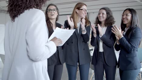 businesswomen applauding to colleague with papers