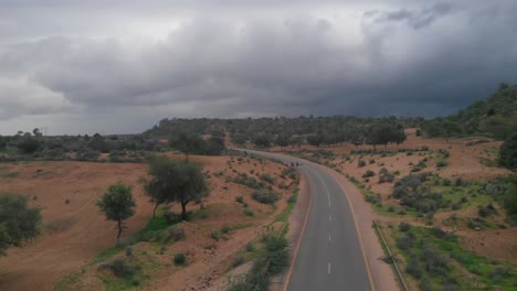 Vuelo-Aéreo-Sobre-Una-Carretera-Remota-A-Través-De-Tharparkar-En-Sindh-Con-Nubes-De-Mal-Humor-Cubiertas