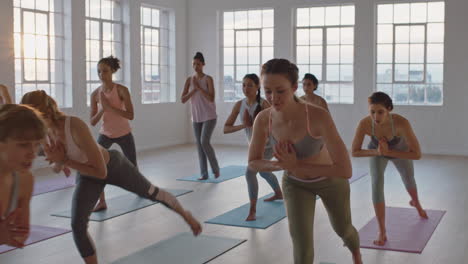 yoga-class-of-healthy-women-practicing-warrior-pose-enjoying-exercising-in-fitness-studio-instructor-leading-group-meditation-teaching-workout-posture-at-sunrise