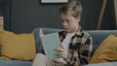 boy reading a book on a couch