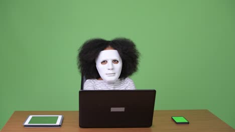 joven chica africana con cabello afro como hacker usando una computadora portátil