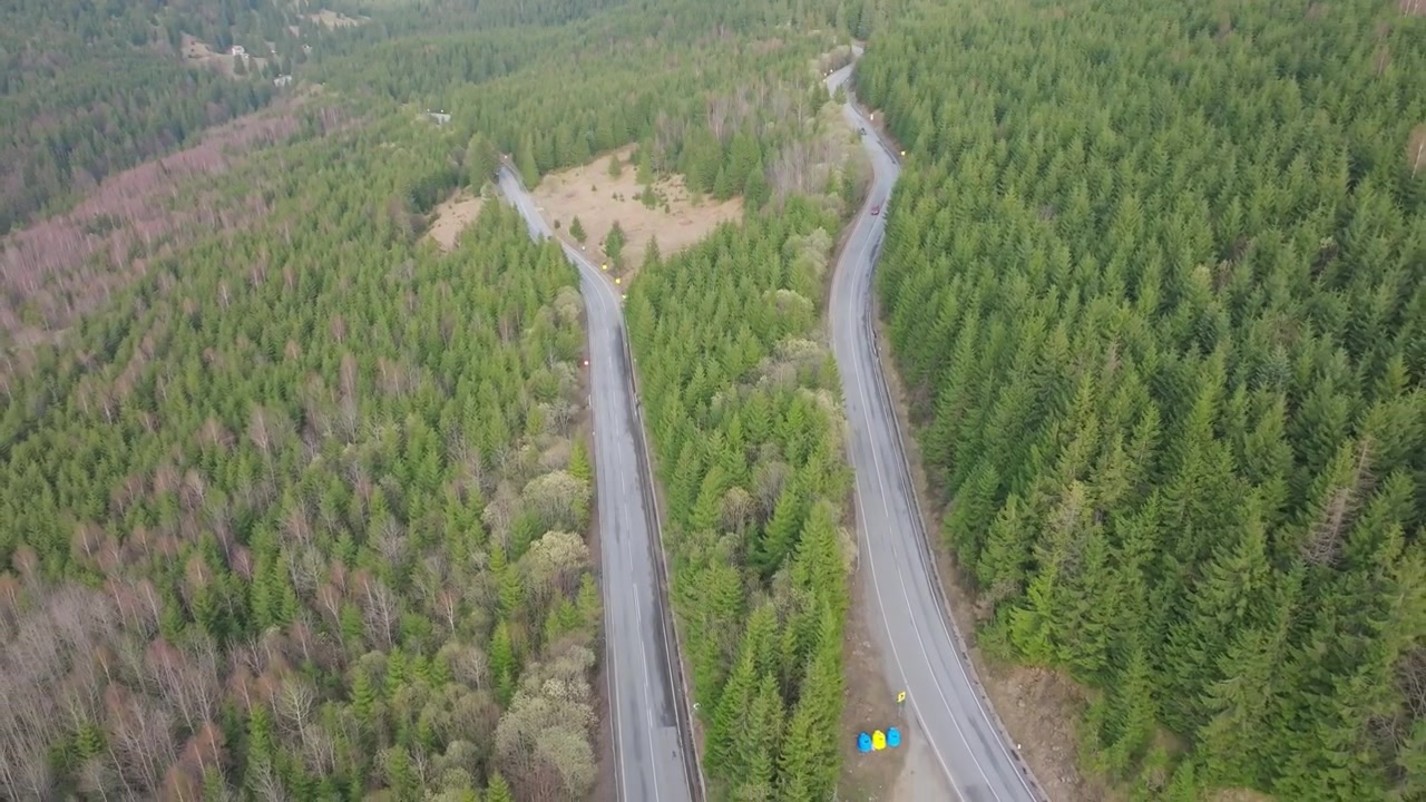 Drone lentää taaksepäin metsätien risteyksen yläpuolella ajoneuvoineen Rodneissa, Romaniassa.