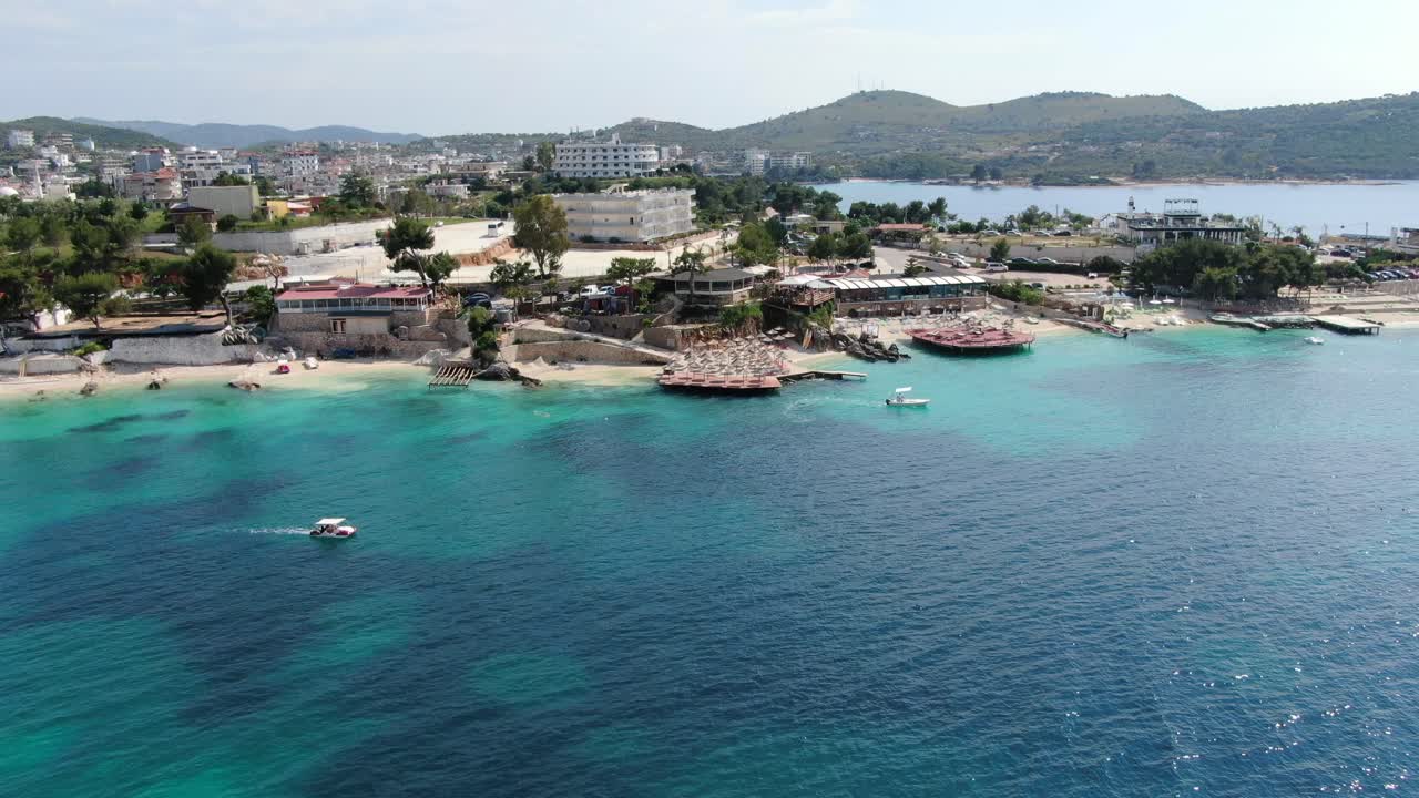 알바니아에서 드론이 으로 날아다니며  모래 해변, 푸른 크리스탈 은 물, 초록색 작은 섬, 배와 호텔, 사밀의 빛 날