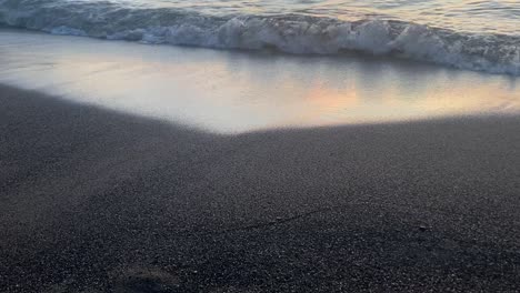 waves arrive on the shoreline and wash the sand at sunset at an italian beach in tuscany