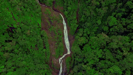 waterfall falling on red rocks in the bijagual ecological reserve in costa rica