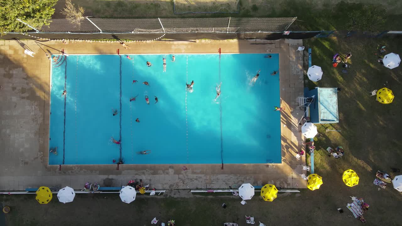 Vista aérea de uma piscina pública azul em um clube na cidade de Buenos Aires ao pôr do sol.