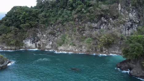 carretilla aérea que revela el verdadero tamaño de un gran acantilado rocoso en la costa de costa rica y un gran nido de pelícanos frente a él