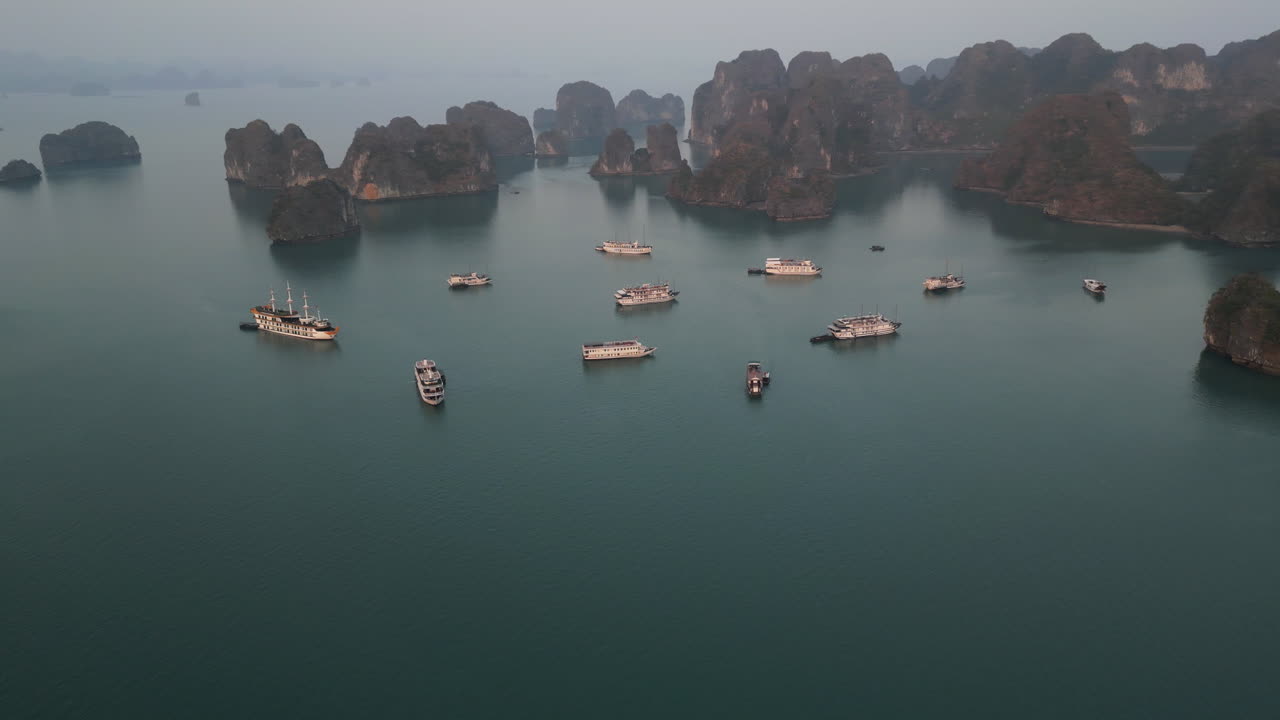 Aerial 4K drone footage over Ha Long Bay, Vietnam, showing tourist boats navigating among limestone karsts and emerald waters