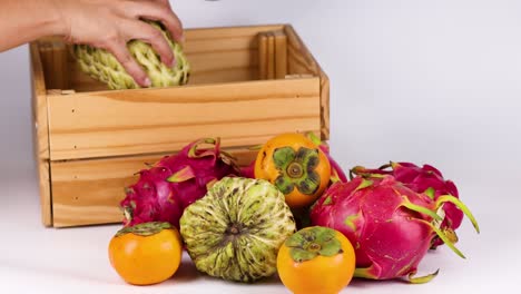 hands placing various fruits into a crate