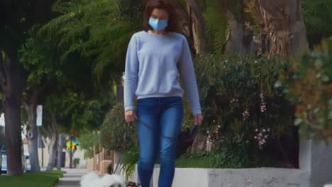 [cámara utilizada: canon c300] mujer caucásica con una máscara quirúrgica mientras paseaba con su perro