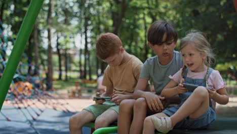 group friends using mobile phone at the playground in summer day.