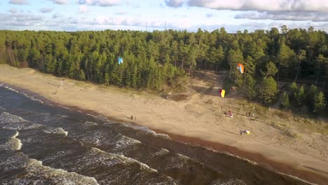 paragliders hovering above a beautiful beach using onshore breeze