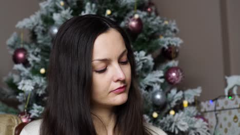 un primer plano de una atractiva mujer caucásica cerca de un árbol de navidad decorado