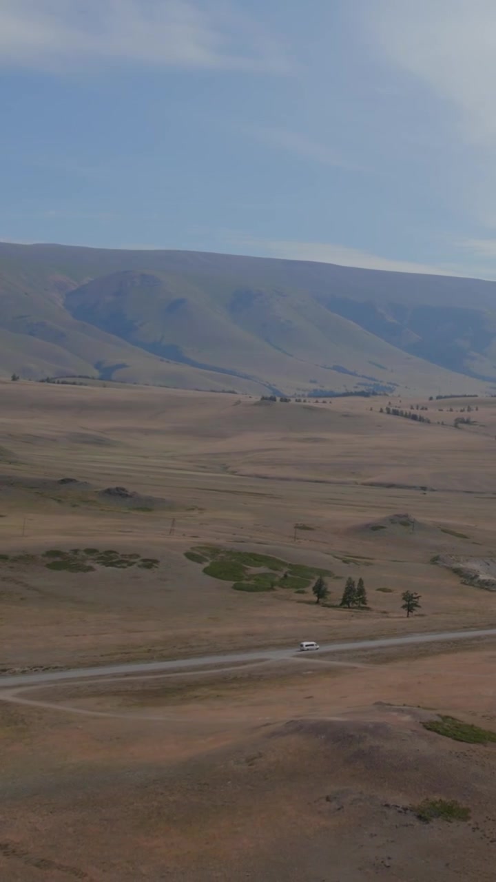 Rusya, Altay Cumhuriyeti'ndeki Kurai Bozkırı üzerinde yüksek drone çekimi; kuru otlakları, kıvrımlı toprak yolları ve yumuşak bir gökyüzü altında puslu uzak dağ sırtlarıyla çevrili geniş, açık bir vadiyi gözler önüne seriyor