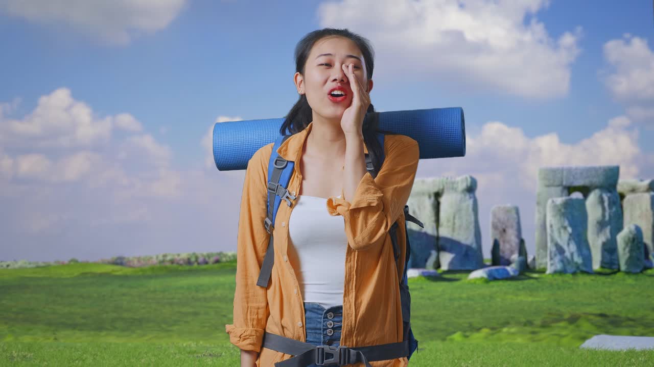 Asian Female Hiker With Mountaineering Backpack Screaming Holding Hands Near Her Mouth While Traveling In Stonehenge