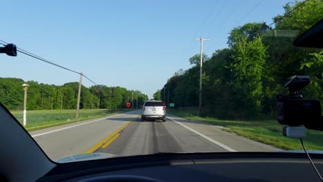 a car drives down a rural road with traffic signs and trees lining the sides. perfect for travel, transportation, or countryside footage.