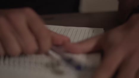 close up of a man's hands writing in a notebook