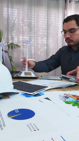 engineer's desk with calculator and green energy models