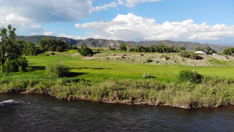 green vibrant lush colorado countryside scenery with flowing river creek and mountain range