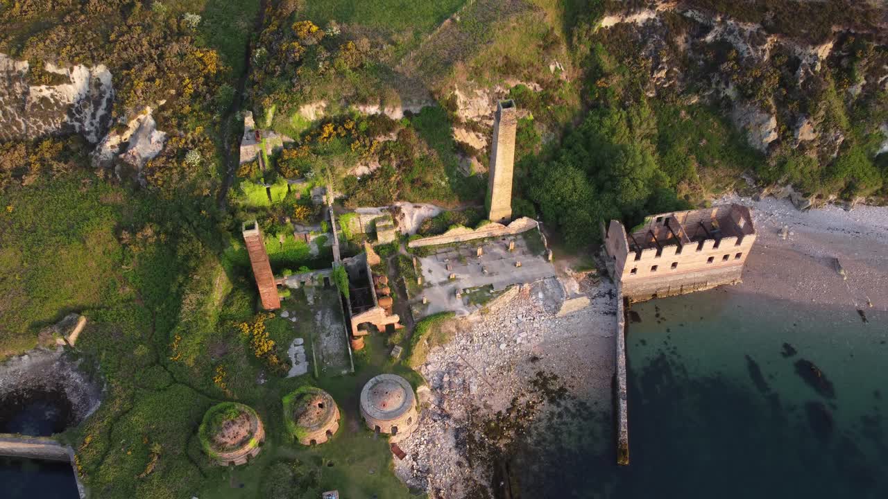 porth wen 버려진 해안의 버려진 벽돌 공장은 황금빛 일출 시골 베이 조감도에서 추적 샷을 제거합니다.