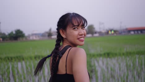 couple holding hands while walking through a green rice field