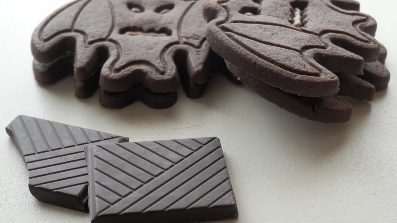Bat biscuits and pieces of chocolate bars - Halloween sweets - light camera pan