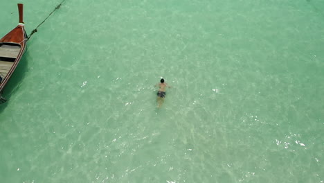 Man-swiming-breaststroke-near-a-boat-on-clear-ocean-water-in-slow-motion