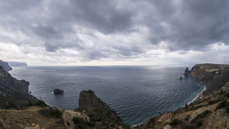 timelapse on overcast day with rain-snow cumulonimbus clouds, moving through the sky at different heights, with parallax effect over sea lagoon and rocky hills. nature and outdoors travel concept