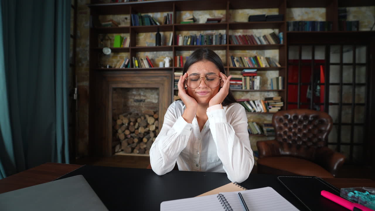 mujer con dolor de cabeza en el escritorio de la oficina o la biblioteca