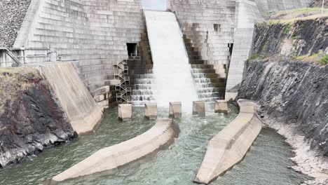 water flows over dam spillway into river