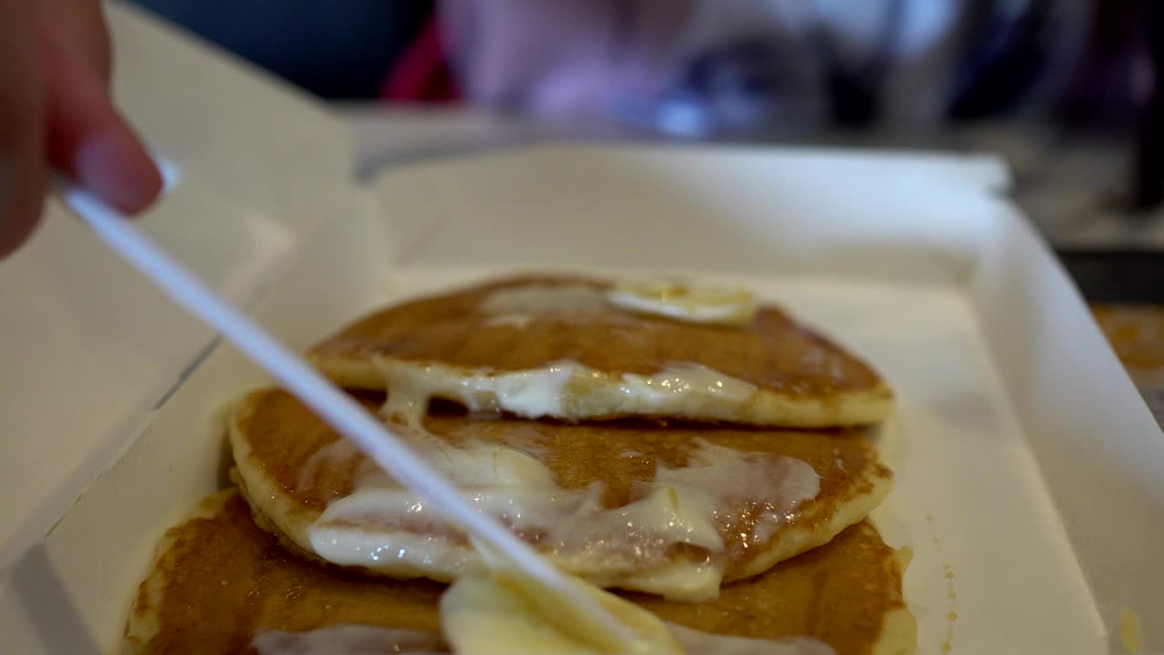 아이는 칼과 포크로 아이의 손을 고 크림을 팬케이크에 뿌립니다.