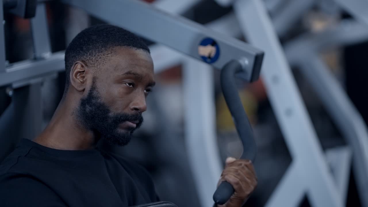 A focused African American man performing a one armed lat pull down