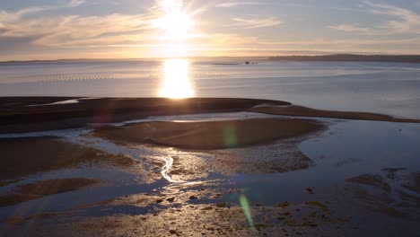 puesta de sol sobre una bahía costera con granjas de ostras