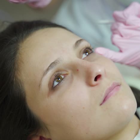master is making a permanent eye makeup for a woman in a beauty salon. equipment for permanent makeup