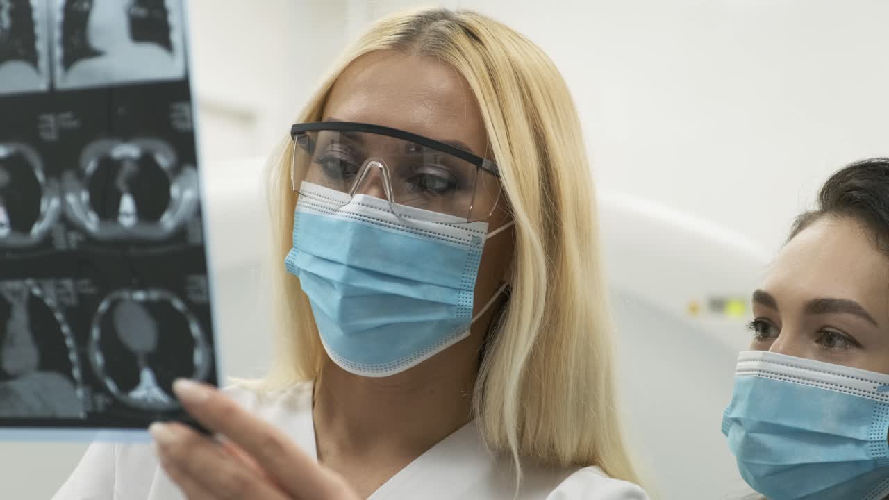 la radióloga explica los resultados de la tomografía computarizada para una paciente joven, mostrando la instantánea con imágenes, observando y analizando la tomografía computada en una clínica moderna junto a un escáner computarizado moderno