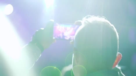 spectators with phones in their hands at a music festival. multicolored light at a music festival