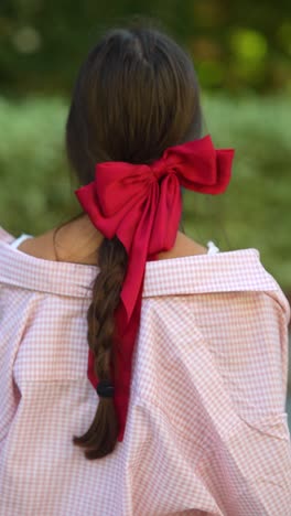 woman with red bow in her hair and pink checkered shirt