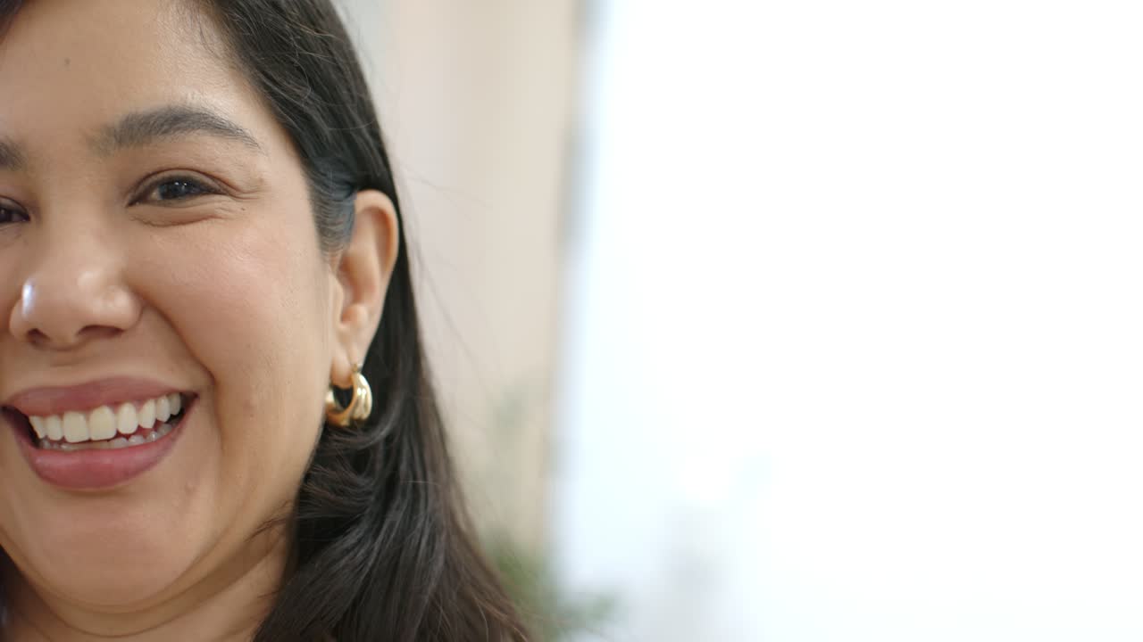 Donna sorridente, che si allarga mentre la camera rivela il lato sinistro del volto in studio con orecchino a cerchio dorato, spazio per il testo