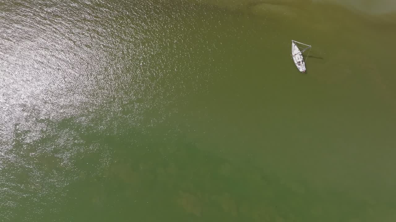 Nadir drone view of several small boats moored over green open water near the tidal edge; top‑down angle in daylight