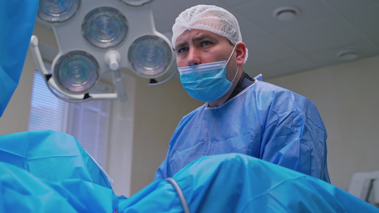 Portrait of a surgeon in mask at work. Specialist looking seriously at something during the operation in clinic. Medicine concept.