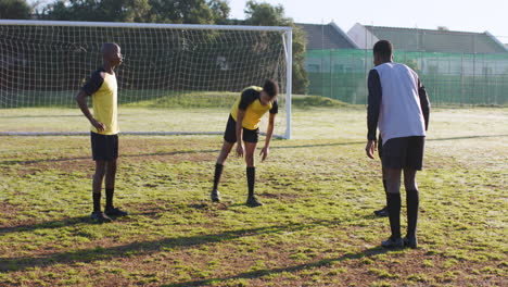 soccer players stretching on field, preparing for practice with coach guiding