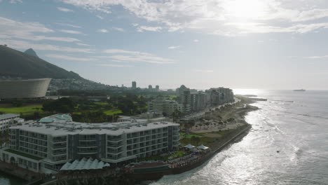 Hotels-and-apartment-buildings-along-sea-coast.-Waves-rolling-to-shore-and-washing-beach.-Mouille-Point-urban-borough.-Cape-Town,-South-Africa