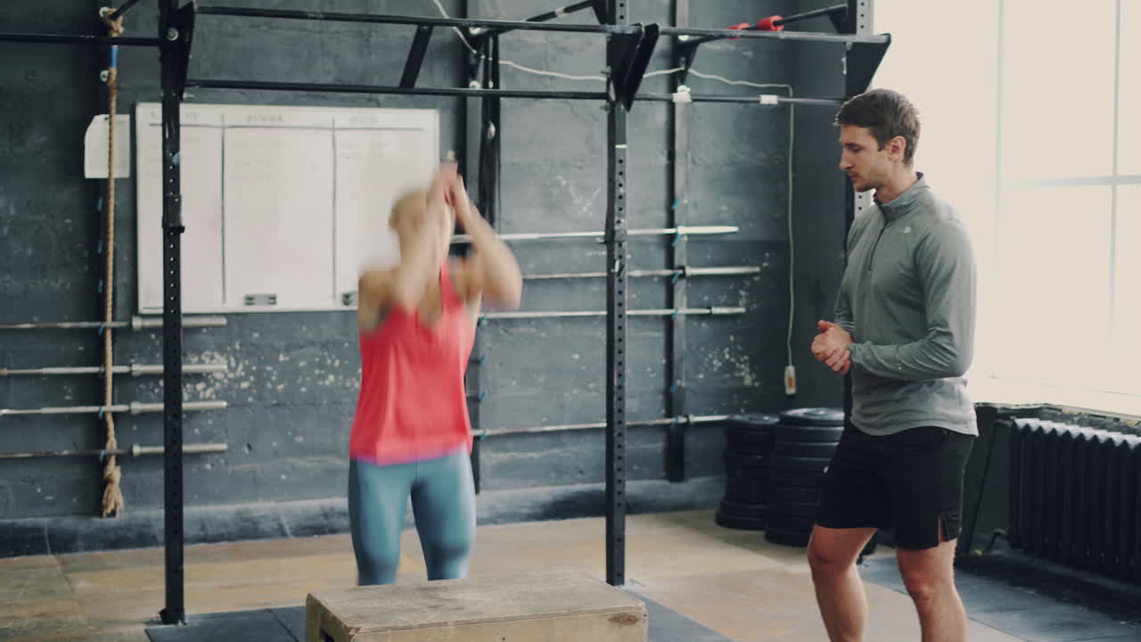 Woman performing box jump with trainer watching