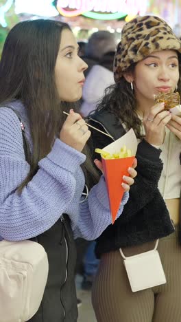 young women enjoying street food at a fair